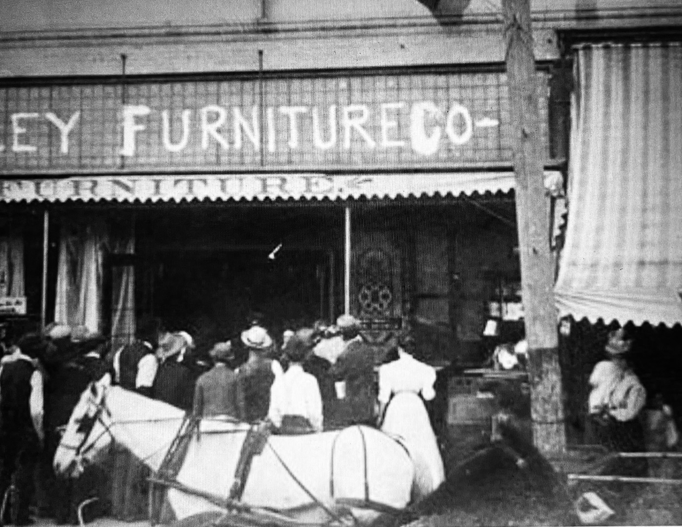 An early-1900s Glassell Street storefront with a gathered crowd