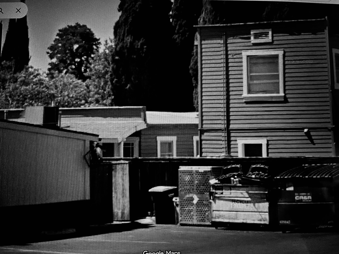 A shadowed clapboard building behind the Plaza, in black and white